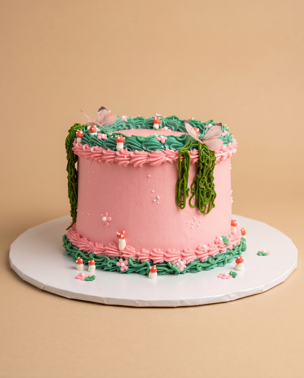 Pink fairy garden buttercream cake with piped green vines, red toadstool mushrooms, and butterfly accents