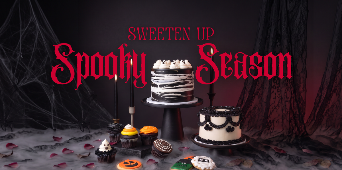 Halloween-themed Sweet Lady Jane dessert display featuring decorated cakes, cupcakes, and cookies surrounded by candles, cobwebs, and fog with “Sweeten Up Spooky Season” text.