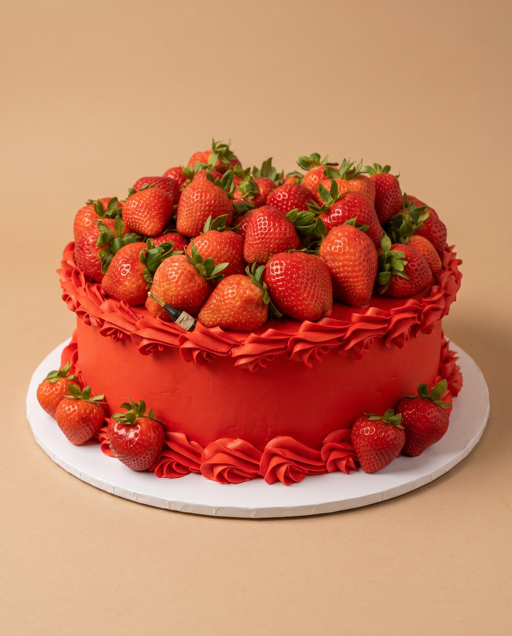 Red buttercream cake piled high with fresh strawberries and decorative red piped ruffles