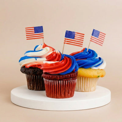 Three chocolate, red velvet, and confetti cupcakes with red, white, and blue swirled buttercream and mini American flag toppers